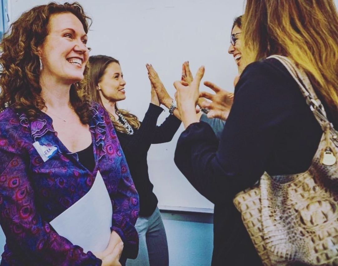 A group of professional partners laughing and high-fiving together