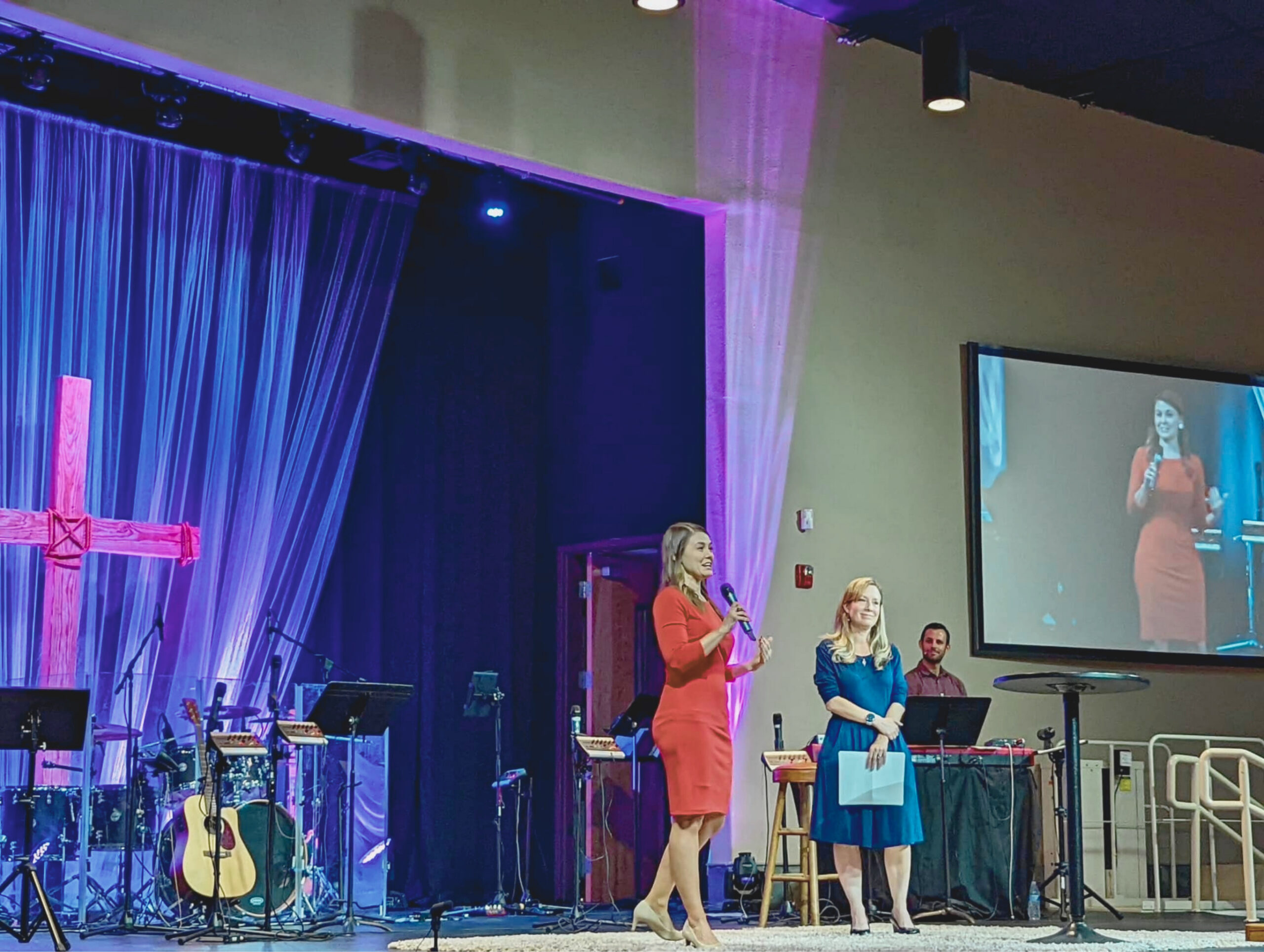 Jennifer Evans speaking at a church during a Living Set Apart faith-based youth event, beside a lit cross backdrop