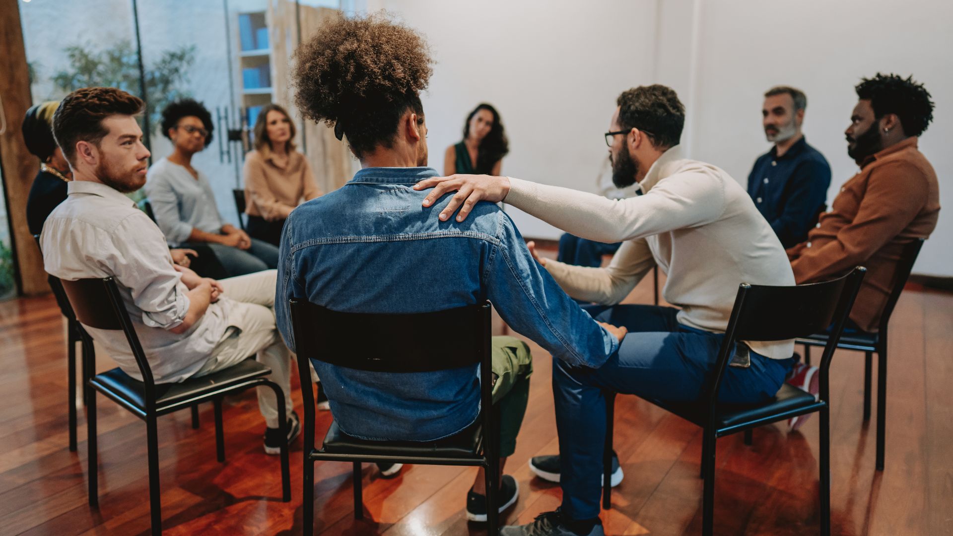 A recovery support group sitting in a circle, offering comfort and encouragement to one another