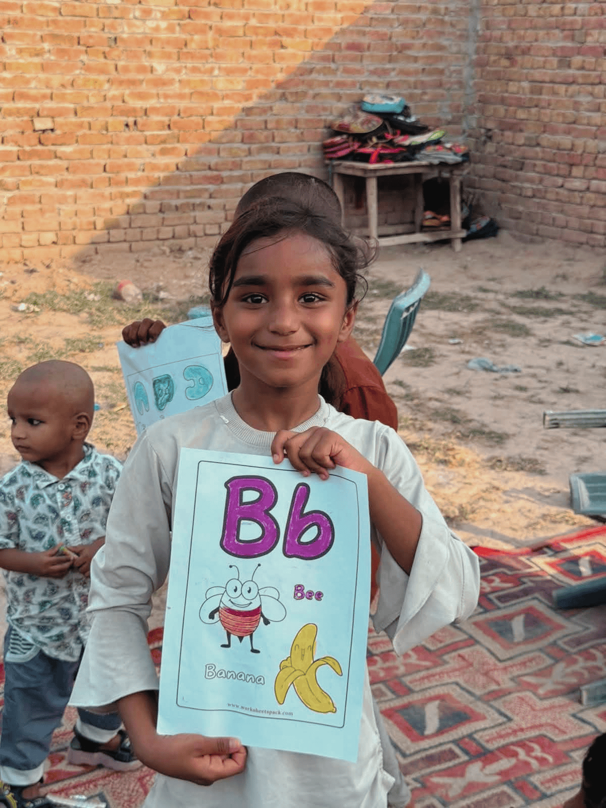A young girl proudly holding up her finished worksheet at the summer camp